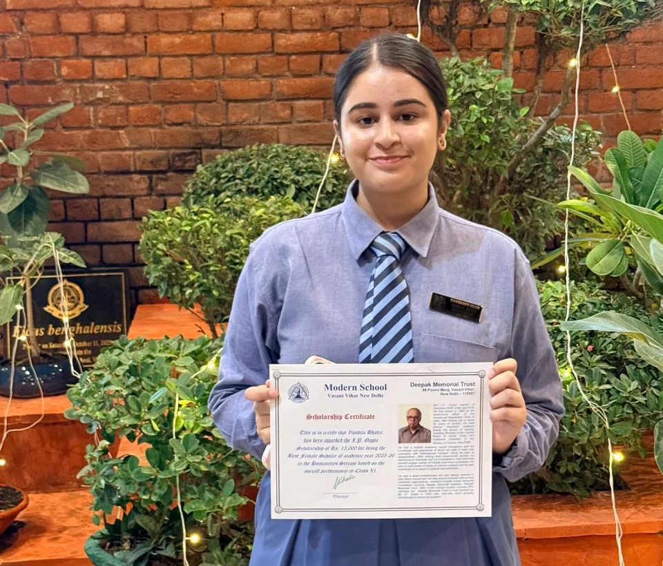 Vandita holding her Deepak Memorial Trust scholarship certificate at school